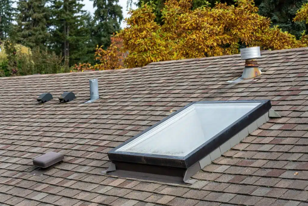 Close-up of a residential roof featuring a new skylight and code-compliant ventilation installed by a trusted Peoria roofing company