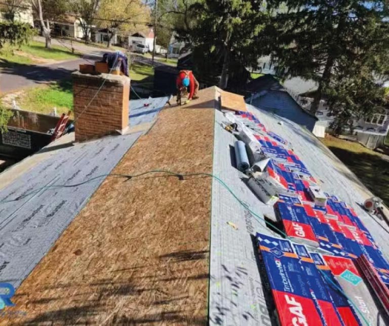 Full view of a modern residential home during the final stages of a professional roof installation and cleanup.
