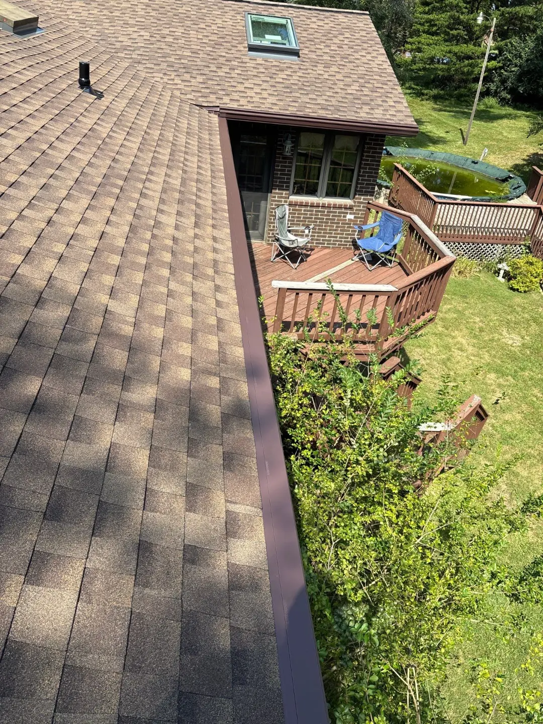Close-up of a new brown seamless gutter, fascia and soffit with downspout on a brick home