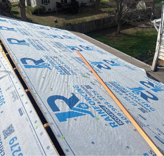 Roof deck covered with Rainforcing Roofing branded synthetic underlayment during a roof replacement in Central Illinois